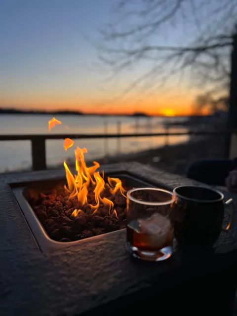 Evening view from the deck with a tabletop fire pit and drinks against a sunset over the water